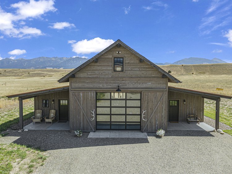 A barn with a garage in the middle of a field