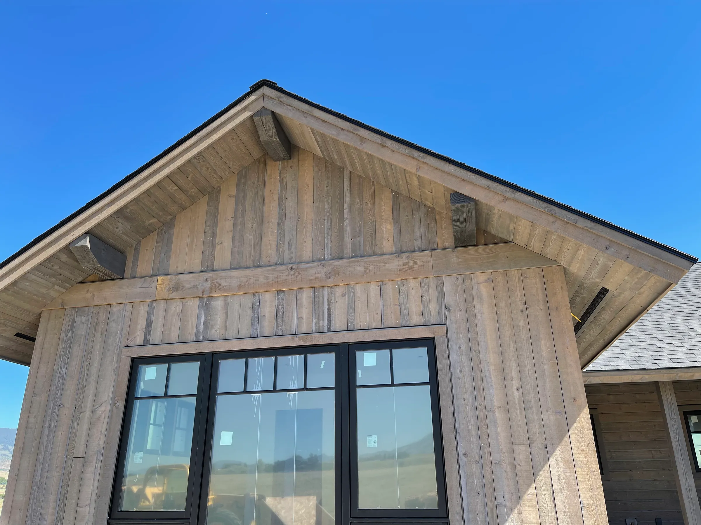 Natural wood board-and-batten siding with black-framed windows
