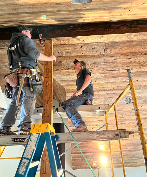 A couple of men standing on top of a ladder