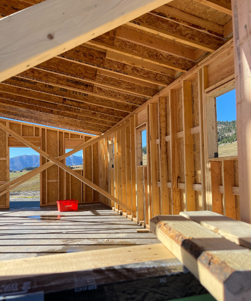 A house under construction with a red bucket in the foreground